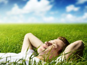 picture of a fellow sleeping on grass under a blue sky with clouds